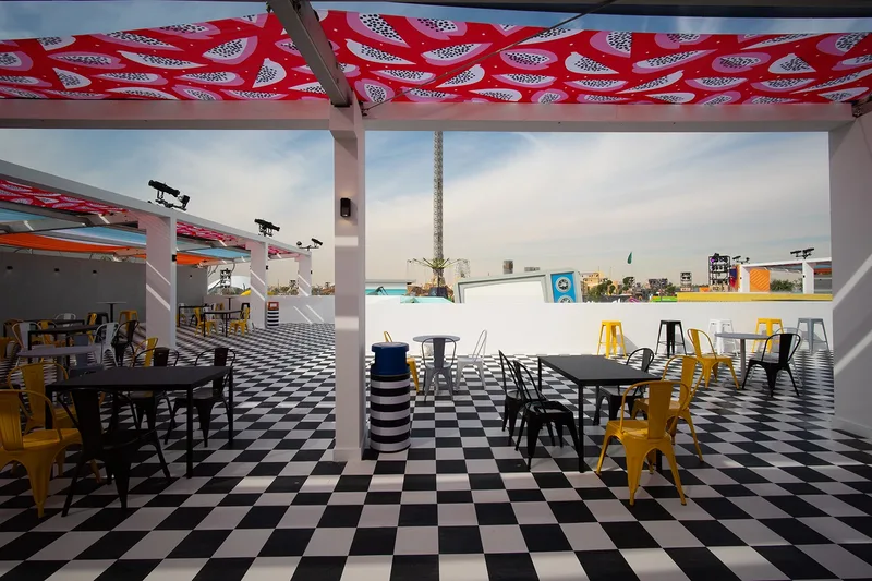 Shaded outdoor dining deck featuring vibrant pink patterned canopy and checkerboard floor built by Evolution Events