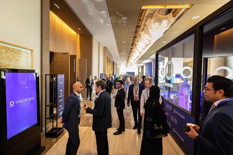 Investopia networking corridor with branded digital signage, media installations and delegates in discussion